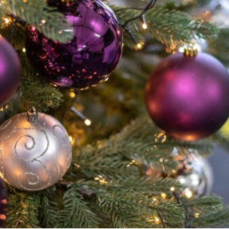 Decorative Christmas tree with purple and silver ornaments.