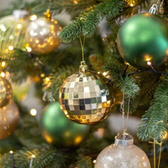 Decorative Christmas tree with green and gold ornaments and lights.