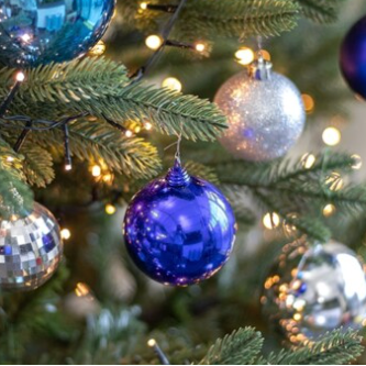 Decorative Christmas tree with blue, silver, and gold ornaments and twinkling lights.